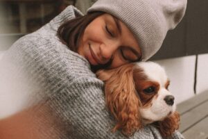 woman hugging a cavalier king charles puppy